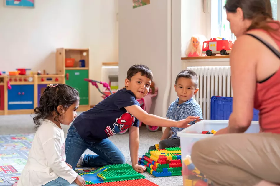 Kinder spielen lachend auf dem Boden – Bild aus einem Projekt der NGO HEKS.