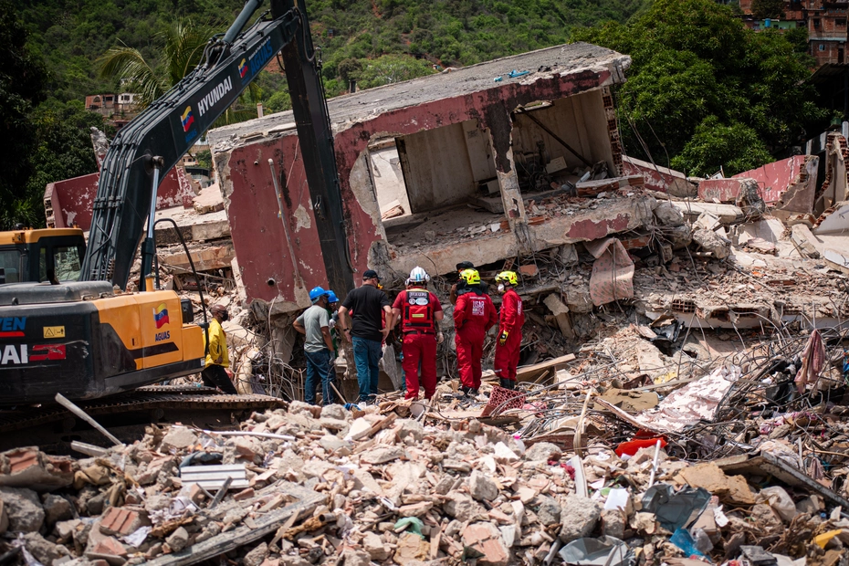 Rettungskräfte und ein Bagger stehen vor den Trümmern eines eingestürzten Gebäudes nach dem Erdbeben in Venezuela.