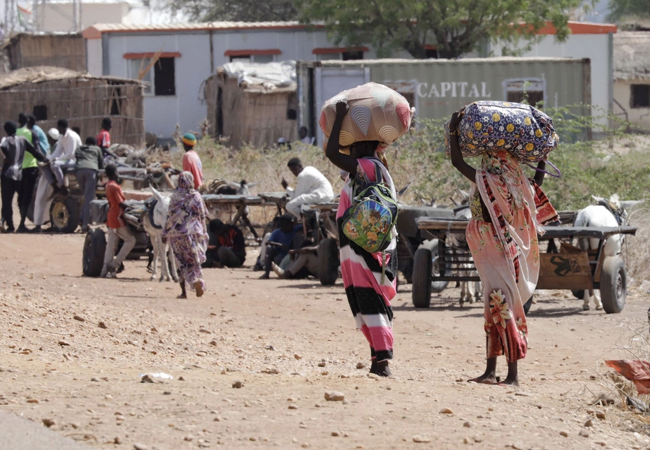 Flucht über die Grenze nach Südsudan Sudanesische Flüchtlinge und südsudanesische Rückkehrer tragen ihr Hab und Gut über den Grenzübergang Joda – auf der Suche nach Schutz vor dem Krieg und versorgt durch humanitäre Hilfe in Renk.