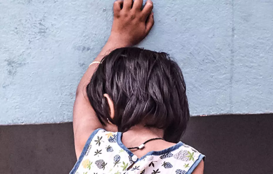 Hilfe für verletzliche Kinder Ein Kind lehnt mit der Hand an einer Wand – ein stiller Appell für Kinderhilfe.