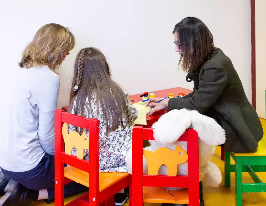 Zwei Frauen begleiten ein Kind beim Spielen in einem geschützten Raum – ein Beispiel für gezielte Kinderhilfe, emotionale Unterstützung und nachhaltige Hilfe im Alltag.